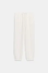 Pantalón jogger color gris claro, de tiro alto con cintura elástica ajustable con cordones, bolsillos delanteros y traseros con solapa, y puños elásticos en los tobillos.