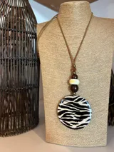 Collar largo con cordón de cuero marrón, cuentas de madera y dije circular con estampado de cebra.