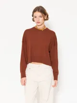 Sweater tejido suave y flojo, color crudo, con cuello redondo y mangas largas.