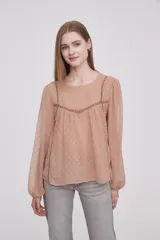 Blusa color beige oscuro con textura de lunares, cuello redondo y mangas largas abullonadas.