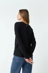 Remera negra de algodón, de corte recto, manga larga y cuello redondo.