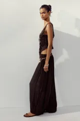 Top marrón con escote redondo y tirantes finos. Tejido fruncido con lazadas frontales y bajo asimétrico con encaje.