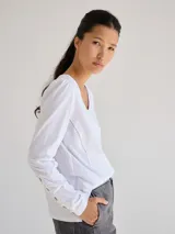 Remera blanca de algodón con escote redondo, mangas largas y pespuntes verticales a contratono.