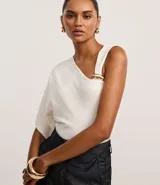 Blusa de punto color crudo, con escote en V y mangas asimétricas: un lado con manga corta y otro musculosa. Tiene un adorno metálico dorado en el bretel.