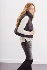 Chaleco puffer negro con cuello alto y cordón de ajuste en el ruedo.