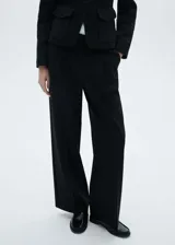 Pantalón negro de corte wide leg, tiro medio, con trabillas, bolsillos laterales y traseros. Cierre frontal oculto con botón, gancho y cremallera.