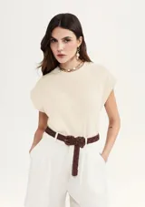 Blusa color crema de tejido acanalado, con cuello redondo y mangas cortas con hombreras.
