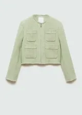 Chaqueta corta color verde claro de tweed con cuello redondo y cierre frontal con cremallera. Tiene cuatro bolsillos de parche en la parte delantera y mangas largas.