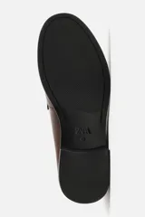 Mocasín de vestir color marrón oscuro, con capellada de cuero, suela a contraste y ligero tacón.