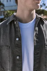 Camisa de denim negra de manga larga con cuello clásico y cierre con botones. Diseño amplio con bolsillos en el pecho.