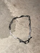Collar plateado con eslabones en forma de llama y dije central de corazón con llamas.
