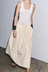 Falda midi de Zara Woman Collection confeccionada en hilatura de algodón color crudo con finas rayas verticales marrones. Tiene tiro medio, cintura elástica ajustable con cordones y bajo evasé.