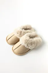 Pantuflas color beige con base de goma y borde superior de peluche.