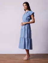 Vestido midi celeste de tencel con cuello a la base y escote en V. Cintura con frunces y lazo de ajuste. Terminación de ruedo con volado.
