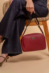 Bandolera pequeña de textura símil cuero color caramelo/marrón, con dos compartimentos principales con cierre. Correa ancha ajustable de tela negra con inscripción en relieve.