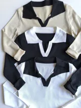Remera de manga larga blanca con cuello polo negro.