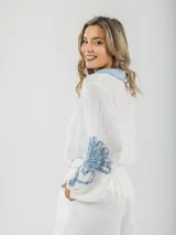 Camisa blanca de tela fresca con cuello camisero celeste y mangas abullonadas con apliques en denim celeste.