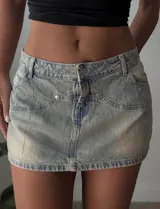 Minifalda de jean celeste con efecto lavado, tiro bajo y bolsillos delanteros y traseros.