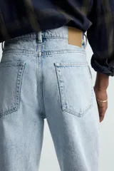 Pantalón de jean celeste de corte recto, con cinco bolsillos, efecto lavado y cierre frontal con botones.