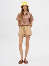 Camisa crop verde con estampado abstracto en tonos naranja y celeste, de mangas cortas y cuello camisero. Confeccionada en viscosa.