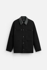 Parka negra de algodón con cuello solapa de cuero sintético, corte recto, acolchada y con cierre frontal de botones.