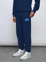 Pantalón de jogging azul marino con puños elásticos y logo de Umbro estampado en celeste en la pierna izquierda.