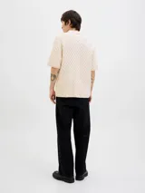 Polo color crema de tejido cable knit con fit relajado, cuello tipo polo, manga corta y cierre con botones.