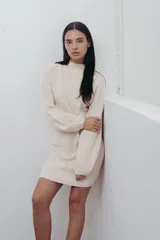 Vestido corto de punto color crema, con cuello alto y mangas globo.