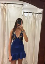 Vestido corto de lentejuelas color verde oliva, con escote en V, breteles finos cruzados en la espalda, cut-outs laterales y volado en el ruedo.