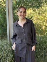 Camisa oversize rosada de lino, con cuello clásico, cierre frontal con botones, dos bolsillos de parche en el pecho y mangas largas con puños abotonados.