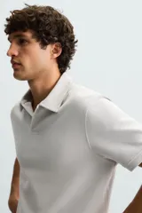 Polo de piqué color crudo, corte regular fit, cuello solapa con cierre de botonadura y mangas cortas.