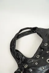 Bolso negro de cuero sintético con tachas plateadas y argollas metálicas.