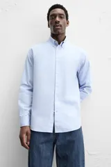 Camisa celeste de algodón, corte relaxed fit, cuello abotonado, manga larga con puños abotonados y cierre frontal con botones.