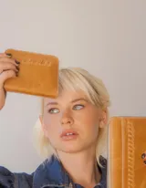 Billetera de cuero color tostado con cierre de cremallera. Interior con seis compartimentos para tarjetas y un compartimento para monedas con cierre. El billete entra doblado.