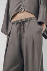 Pantalón blanco de lino, de corte ancho y tiro medio, con cintura elástica ajustable con cordones y bolsillos laterales.