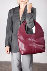 Bolso tote de cuero sintético color borgoña, con asas integradas y logo de la marca grabado en la parte inferior.