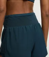 Bermuda deportiva femenina de microfibra color amarillo claro, con diseño de doble capa: un short interno ajustado y una capa externa suelta con bajo redondeado. Posee cintura alta.