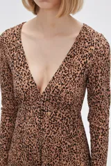 Vestido corto color beige con estampado animal print, escote en V, mangas largas y falda evasé con volados. Ajuste con lazo en la cintura.