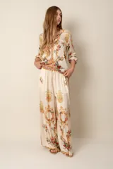 Pantalón palazzo color crema con estampado floral y de arabescos dorados.