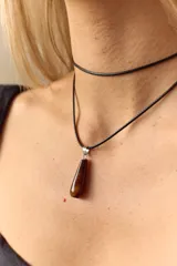 Gargantilla con cordón de cuero negro y dije de piedra natural marrón en forma de gota con engarce de acero quirúrgico.