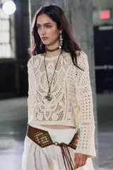 Top color crudo de tejido crochet calado, con cuello redondo y mangas largas acampanadas.