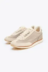 Zapatillas deportivas tipo running color beige y gris claro, con detalles en cuero y gamuza. Cierre con cordones.