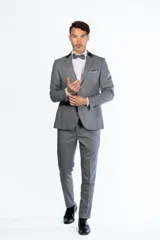 Traje de hombre de dos piezas color azul vibrante, compuesto por saco de un solo botón con solapas de pico en negro y pantalón a juego. Se complementa con camisa blanca, moño azul y pañuelo de bolsillo negro.