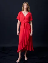 Vestido largo de gasa color rojo, con escote en V, mangas cortas con volados, cintura elastizada con lazo de ajuste y ruedo asimétrico con volados. Tiene forro interno a tono.