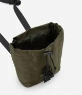 Bolso mini tipo bucket color negro, hecho en poliamida sin estampa. Tiene cierre delantero con tirador y cordón elástico, y tapa con enganche.