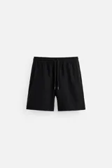 Bermuda negra regular fit confeccionada en tejido de algodón con estructura. Cintura elástica ajustable con cordón, bolsillos laterales y bolsillo trasero de vivo.