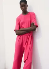 Mono largo color fucsia, de corte recto, con cuello redondo, manga corta y cinturón con hebilla.