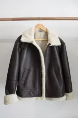 Campera gamulán marrón oscuro con cuello, cierre y puños de piel sintética color crema.