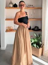 Pantalón de pierna ancha color beige, confeccionado en tencel. Presenta un diseño fluido y holgado con cintura elástica fruncida.