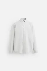 Camisa celeste de corte slim fit, confeccionada en tejido de algodón. Tiene cuello italiano, mangas largas con puños abotonados y cierre frontal con botones.